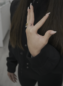 minimalistic tattoo of a moon on the middle finger of a clients hand